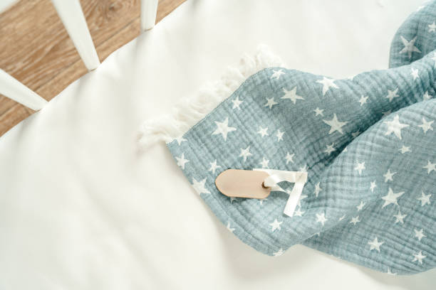 Soft blue muslin blanket hanging on a baby's bed