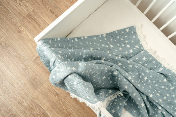 istock Soft blue muslin blanket hanging on a baby's bed 1768219689