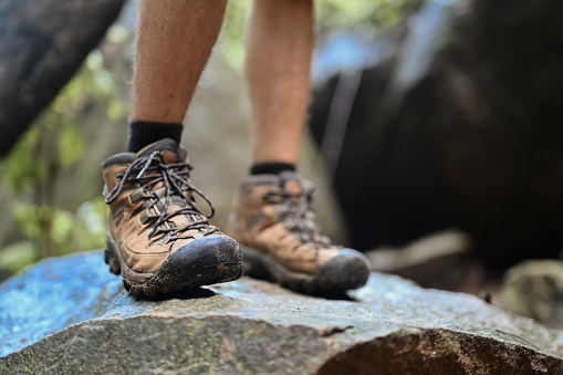 Unrecognizable traveler in trekking shoes standing on a rock. Traveling and adventure concept.