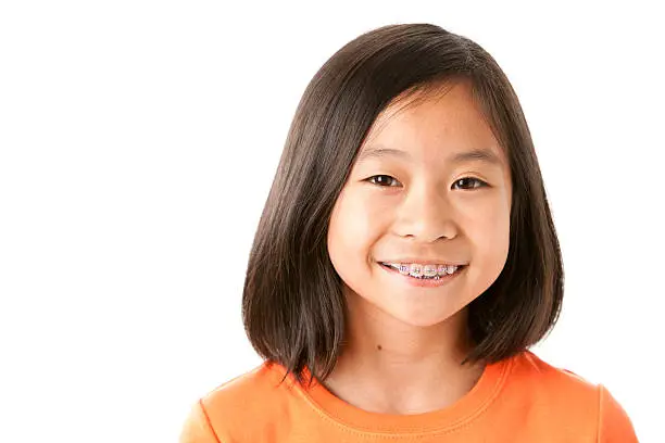 A pretty nine-year old Asian girl shows off her braces with a big smile