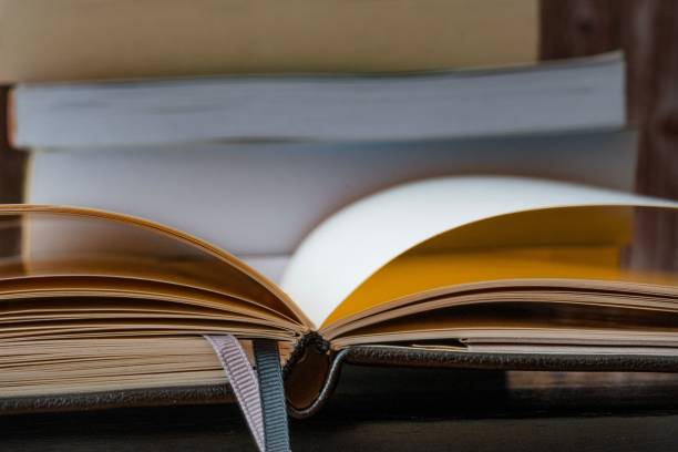 istock Open hardcover book lying on a table surrounded by other books 1768241651