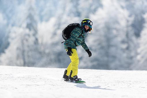 Young happy woman having fun while snowboarding in winter day. Copy space.