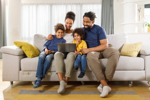 istock Happy black family using laptop on sofa at home. 1768243688