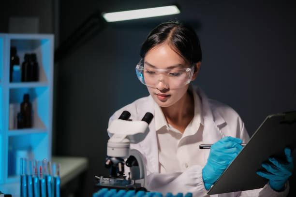 istock Asian female scientist looking under microscope, analyzes petri dish sample. specialists working on medicine, biotechnology research in advanced pharmacy lab, Medical development laboratory. 1768244379