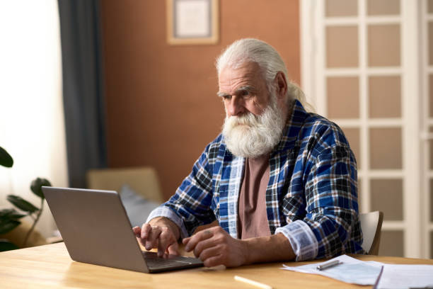 istock Senior man typing on laptop at home 1768245433