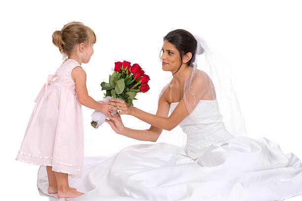 Little Flower Girl in Pink Giving Roses to Bride (Isolated) Brunette bride accepts a bouquet of 2 dozen roses from an adorable young flower girl dressed in pink dress.Isolated studio shot with light reflection at edge of dress. flower girl stock pictures, royalty-free photos & images