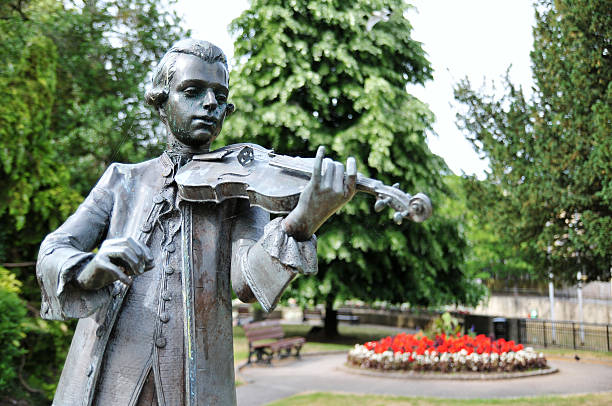 Park Statue Old Bronze Statue in a Public Park of a Young Musician Playing a Violin wolfgang amadeus mozart photos stock pictures, royalty-free photos & images