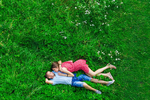 aerial view of couple in the meadow outdoors. guy and girl hugging each other on green grass.