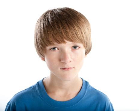 A preteen boy with light brown hair and blue eyes has a serious expression on his face.