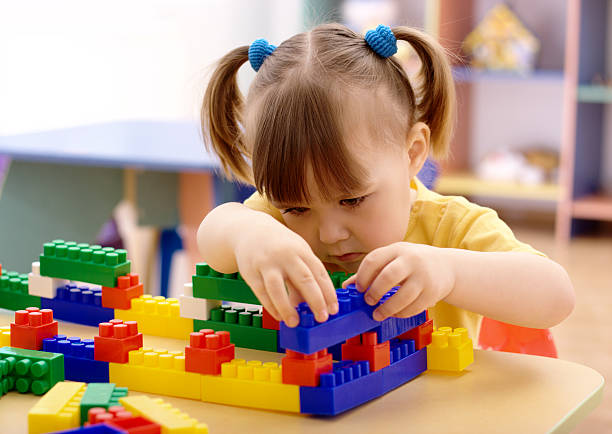 Little girl with pig tails playing with plastic blocks at her seat stock photo