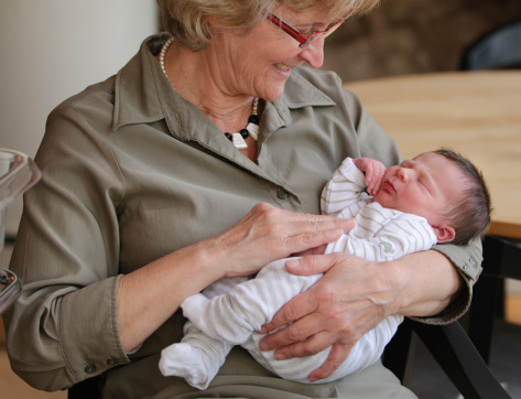 A happy grandmother holding her newborn grandson