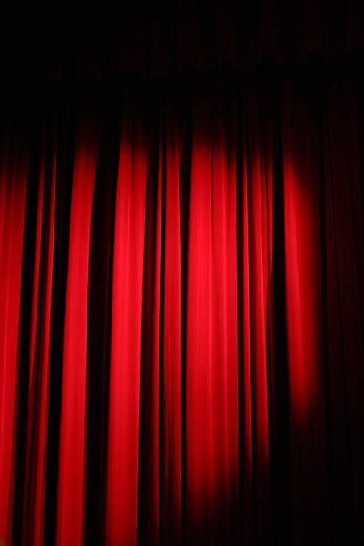 istock Spotlight shining on a velvet red stage curtain 176830073