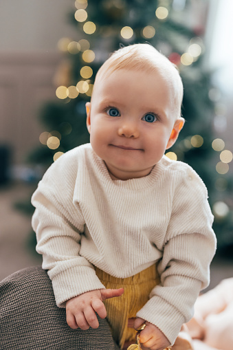 Step into a world of festive delight with this heartwarming scene where an adorable baby smiles brightly during Christmas time at home.