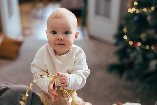 Step into a world of festive delight with this heartwarming scene where an adorable baby smiles brightly during Christmas time at home.