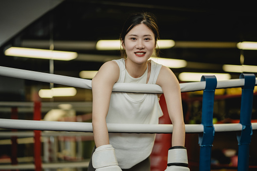 Toned Asian beauty, contact boxing at the gym, happy smile