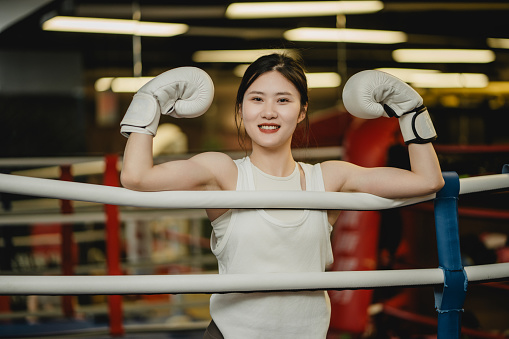 Toned Asian beauty, contact boxing at the gym, happy smile