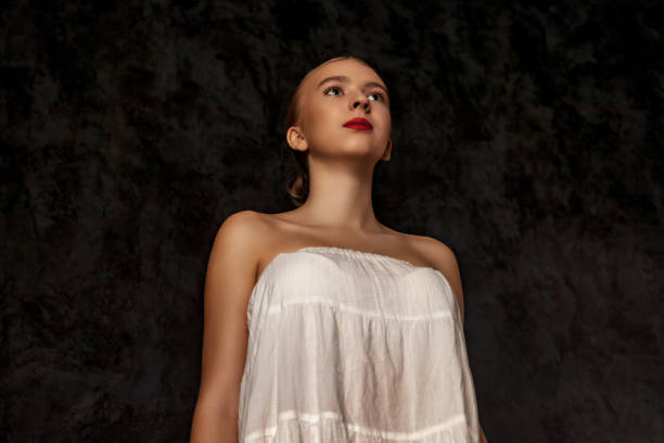 adolescente parfaite dans l’image de poupée posant dans l’ombre sur fond noir, figée regardant ailleurs. portrait d’une belle dame adolescente en blanc, sombre prise de vue en studio. concept de soins de beauté pour le corps. copier l’espace de  - mannequin naked female doll photos et images de collection