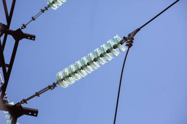 High voltage glass electrical insulator electric line against the blue sky close up.