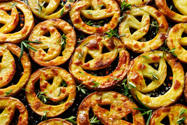 Potato funny snacks with fresh herbs for party on a black background, top view. Baked potato slices with smiles.