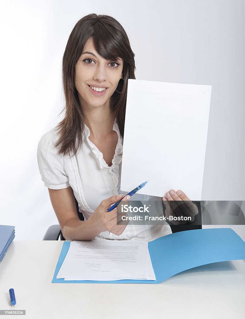 Happy business woman with your message ..Young woman at a desk pointing with her pen to a blank paper. Ideal for inserting your own message. Fine Print Stock Photo