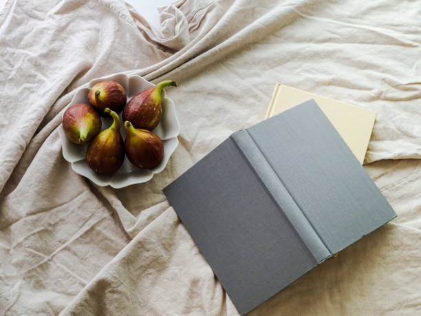 Fig on a White Plate and a grey book, Beige Fabric Background.
