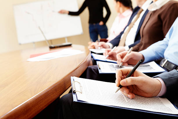 istock Businesspeople at table with pens and clipboards. 176838329