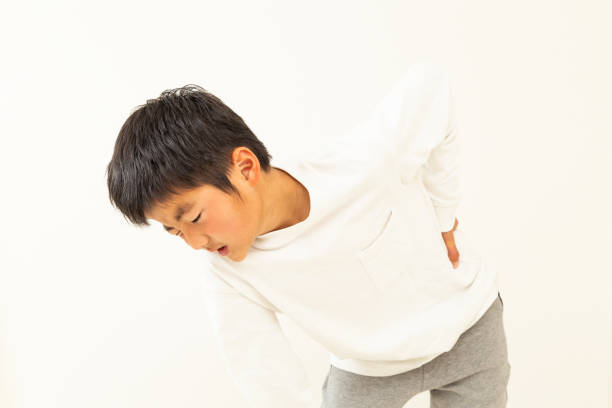 un niño que sufre de dolor de espalda. - 13 14 years teenager 14 15 years child fotografías e imágenes de stock