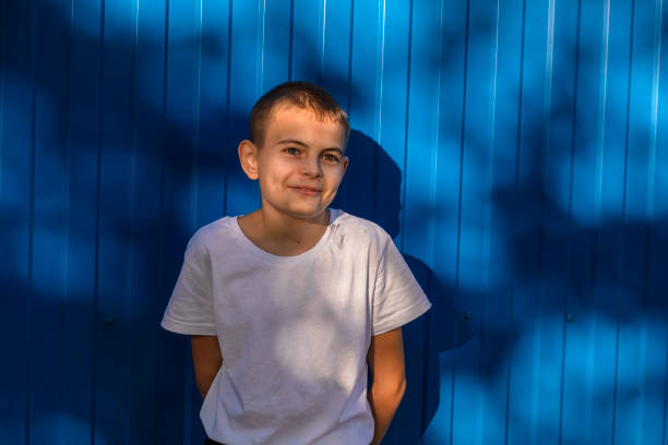 Unbridled Joy: boy smiles Against the Outdoor Blue Wall stock photo