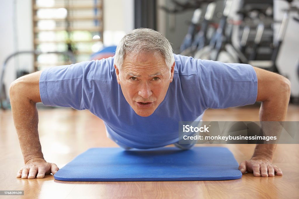 Fit senior man exercising on mat at gym Senior Man Doing Press Ups In Gym, Working Hard 60-69 Years Stock Photo