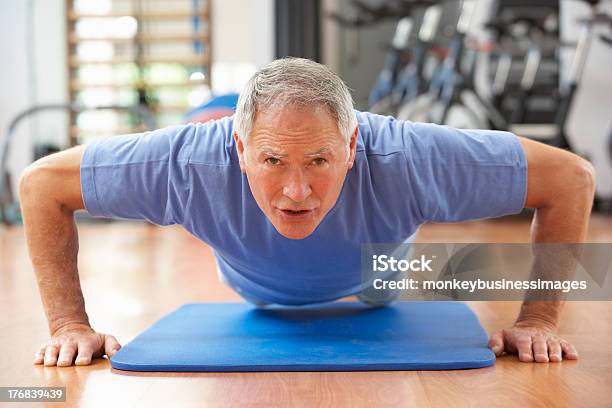 Fit Senior Man Exercising On Mat At Gym Stock Photo - Download Image Now - 60-69 Years, Active Lifestyle, Active Seniors