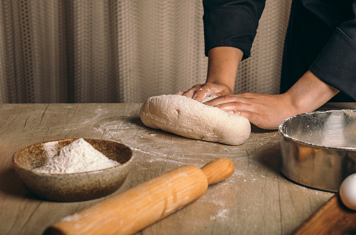 A woman kneads the dough with flour close-up. The cook prepares bread dough