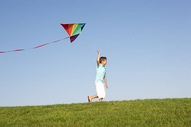 istock Young boy running with kite through field 176839588