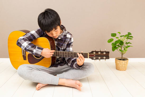 un garçon jouant de la guitare. - 12 13 years 13 14 years learning education photos et images de collection