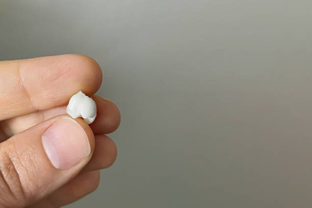 istock White fallen baby tooth in hand on gray background, macro 1768400853