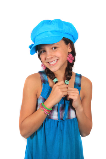 Pretty ten year old adolescent multi ethnic girl with long dark hair on a white background wearing colorful blue hat