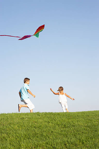 istock Young children run with kite through field 176840639