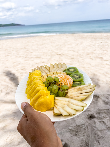 Healthy tropical lifestyle concept
POV of man holding a fruit platter by the beach