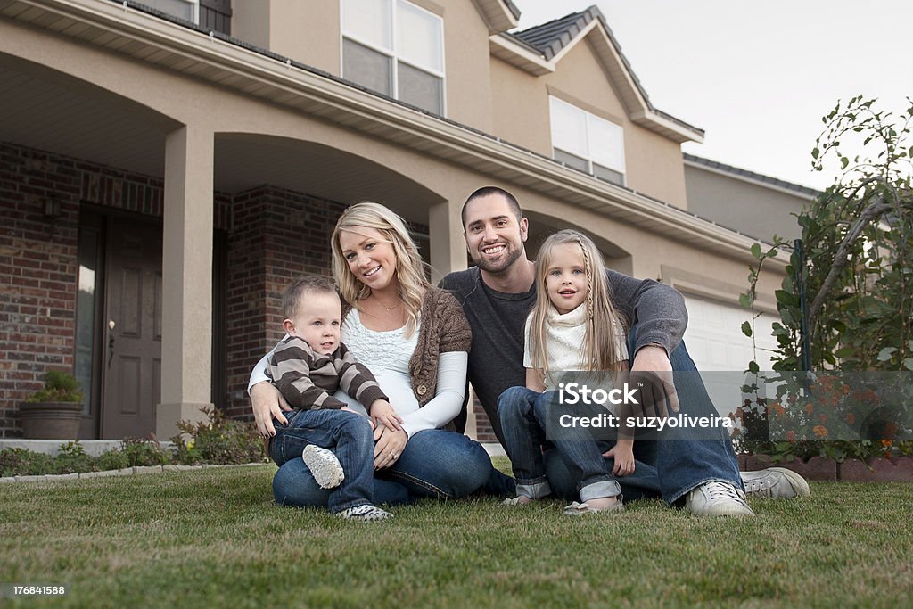 Family in front of their new house A young Caucasian family with a son and daughter sitting in front of their new home.  In Front Of Stock Photo