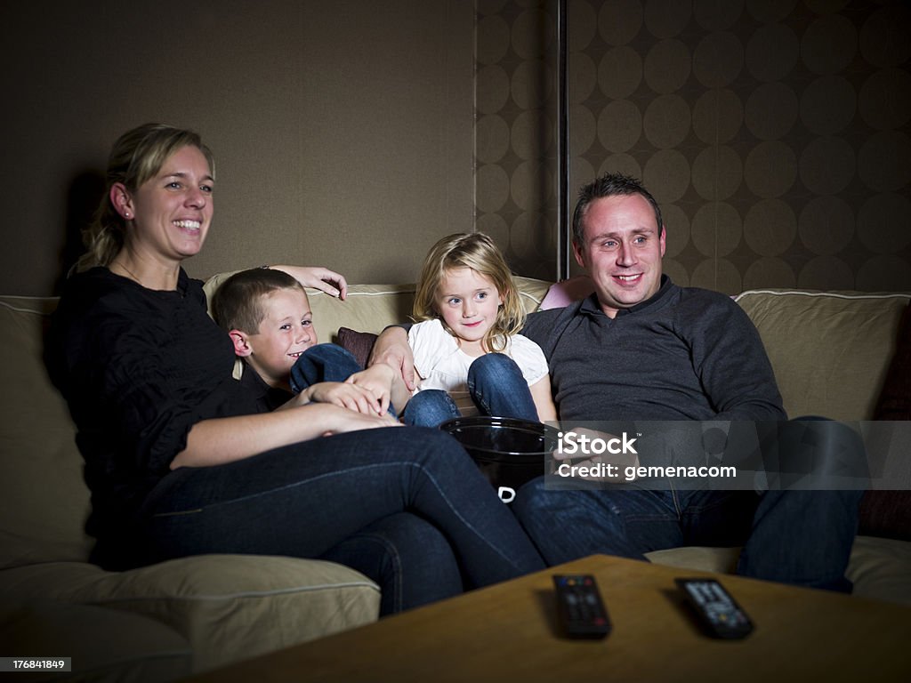 Family in front of the TV Family in front of The Television sitting in the sofa In Front Of Stock Photo