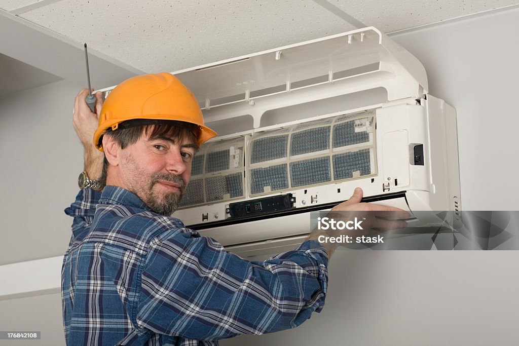 Technician fixing air conditioner Repairer conducts adjustment of the indoor unit air conditioner. Air Conditioner Stock Photo