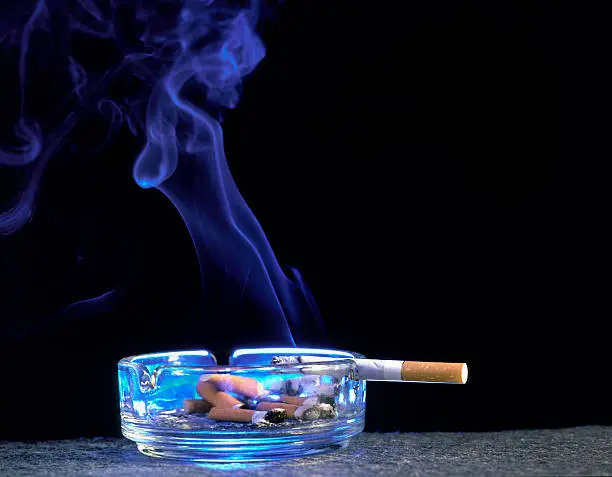 Photo of burning cigarette in ashtray