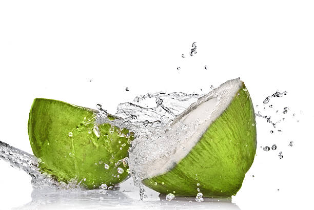 зеленый кокос с брызг воды, изолированные на белом - raw water стоковые фото и изображения
