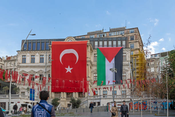 Istanbul, Turkey - October 19, 2023: People on the square in Istanbul with Turkish and Palestinian flags hanging outside in street to show support for people in Gaza region