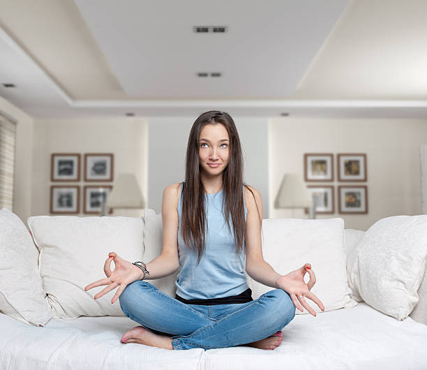 Zen moment at home Young woman sitting on a sofa in the lotus position meditating sooth stock pictures, royalty-free photos & images