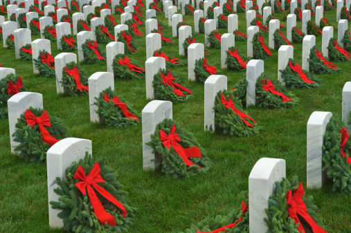 Wreaths with red ribbons adorn the grave markers of military veterans during the holiday season at a national cemetery.