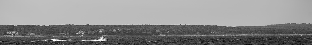 Solitary fishing boat on Nantucket Sound.  It is in the foreground with a morning sky behind it.