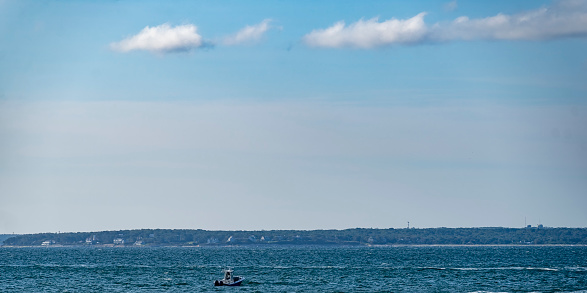 Solitary fishing boat on Nantucket Sound.  It is in the foreground with a morning sky behind it.