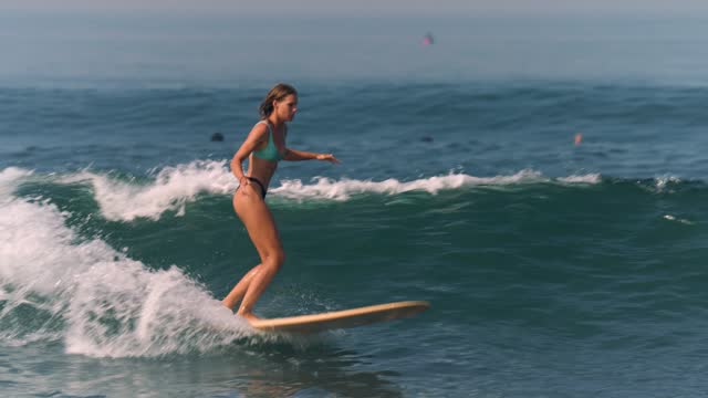 White Woman Surfer Surfing with a Longboard at the Ocean