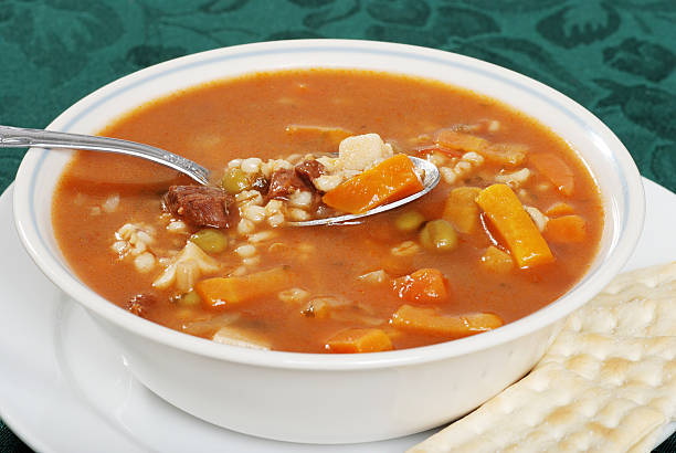 closeup beef barley soup with a spoonful and salted crackers
