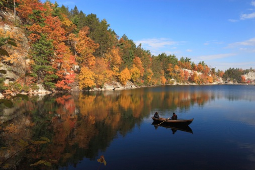 A rowboat silhouetted against the colorful shore of Mohonk Lake in the Shawangunk Mountains of New York
